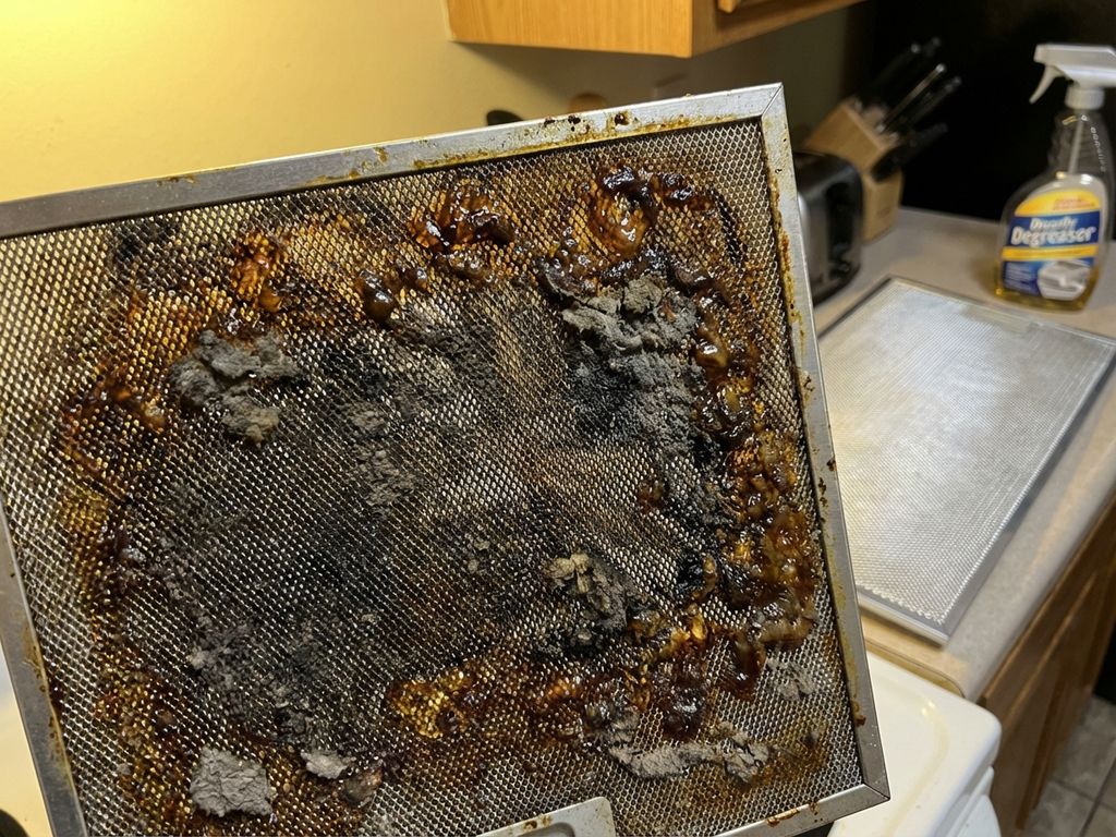 Vervuilde afzuigkap filter met dikke vetlaag en vuil naast schone filter ter vergelijking in keuken