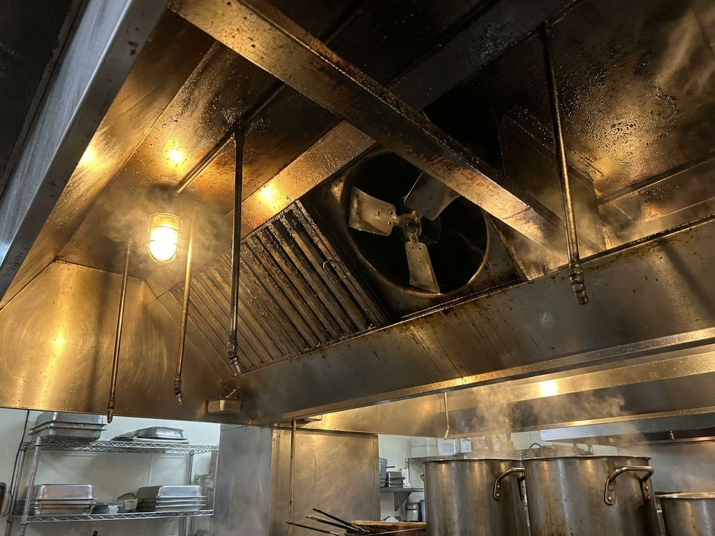 Commerciële keukenafzuigkap met vetophoping en defecte ventilator in professionele restaurantkeuken