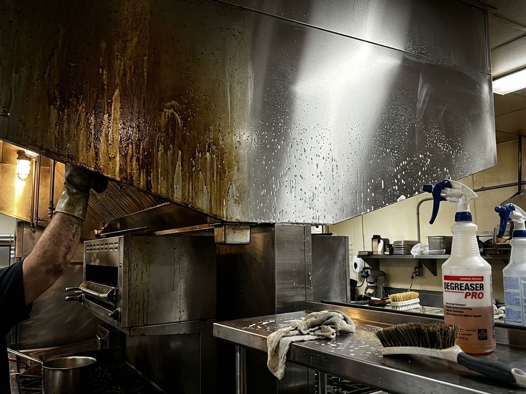 Professionele restaurantkeuken tijdens grondige reiniging toont voor-en-na contrast op roestvrijstalen afzuigkap